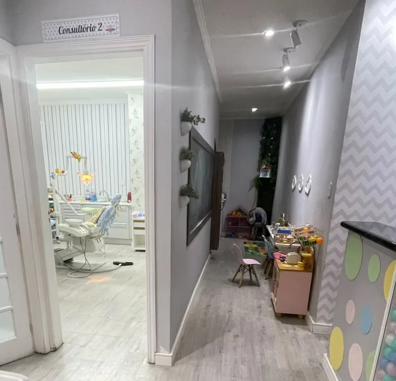 Corredor com a porta do Consultório 2 e, ao fundo, um cantinho com mesinhas e brinquedos.