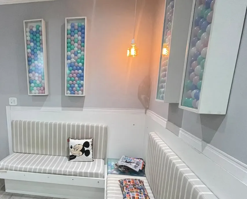 Sala de espera com bancos listrados, almofadas e painéis de parede cheios de bolinhas coloridas.